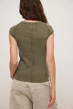 Back view of olive ribbed tee showing exposed center seam and stitched patch detail at neckline.