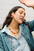 Noonday Collection mini halo earrings styled on model with jacket and necklaces
