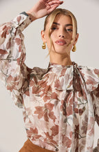 Vintage-inspired sheer blouse styled with dark denim and gold jewelry