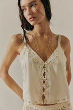 Close-up of embroidered scallop trim and decorative button closures on the Free People cami
