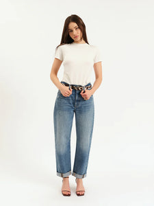 Model wearing DAZE Venice Barrel Long With Cuff jeans in “The Blues” wash. High-rise barrel leg fit with a pre-rolled cuff, styled casually with a tucked-in white tee and heels.