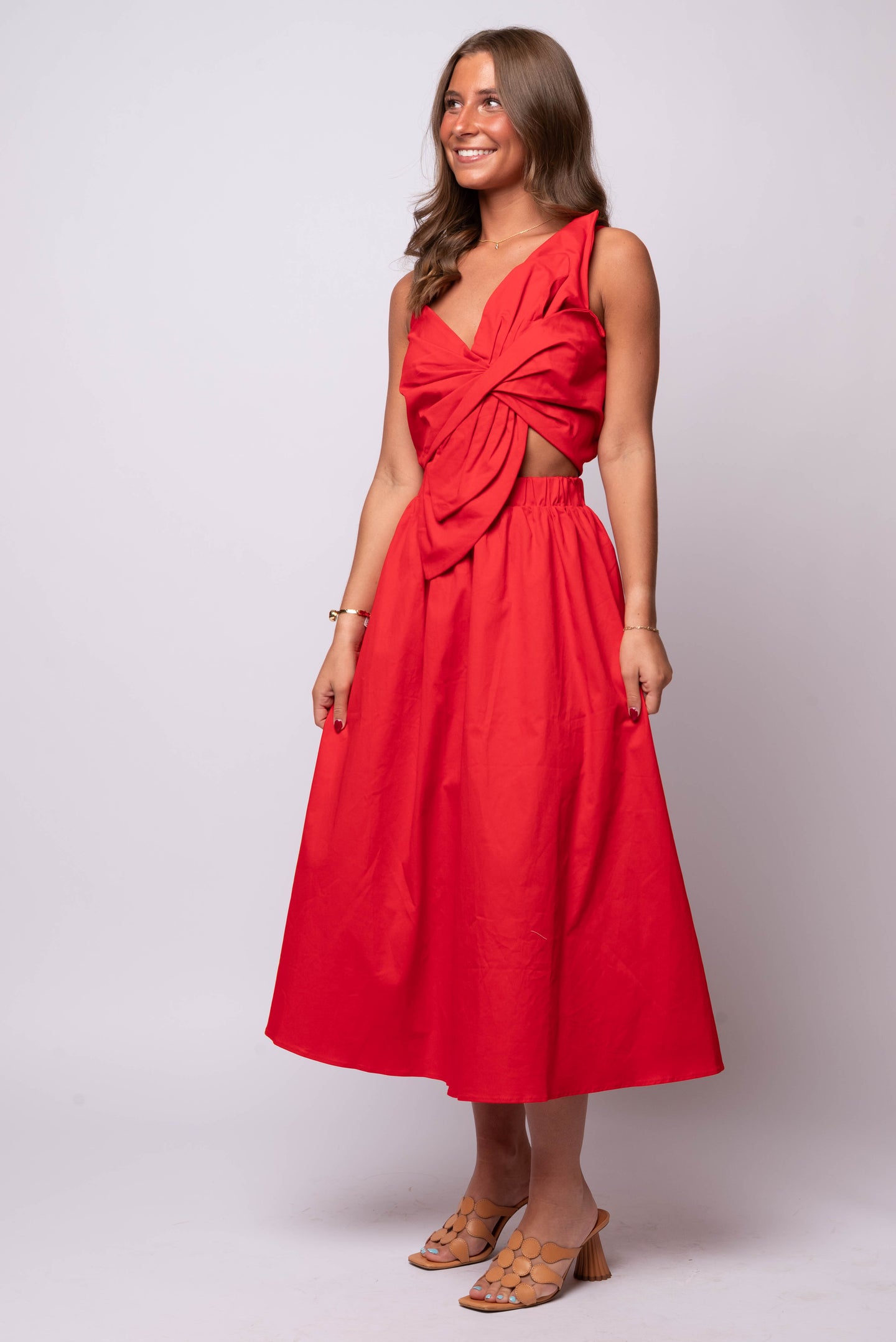 red one-shoulder midi dress with oversized twisted bow, front cut-out, and A-line skirt.