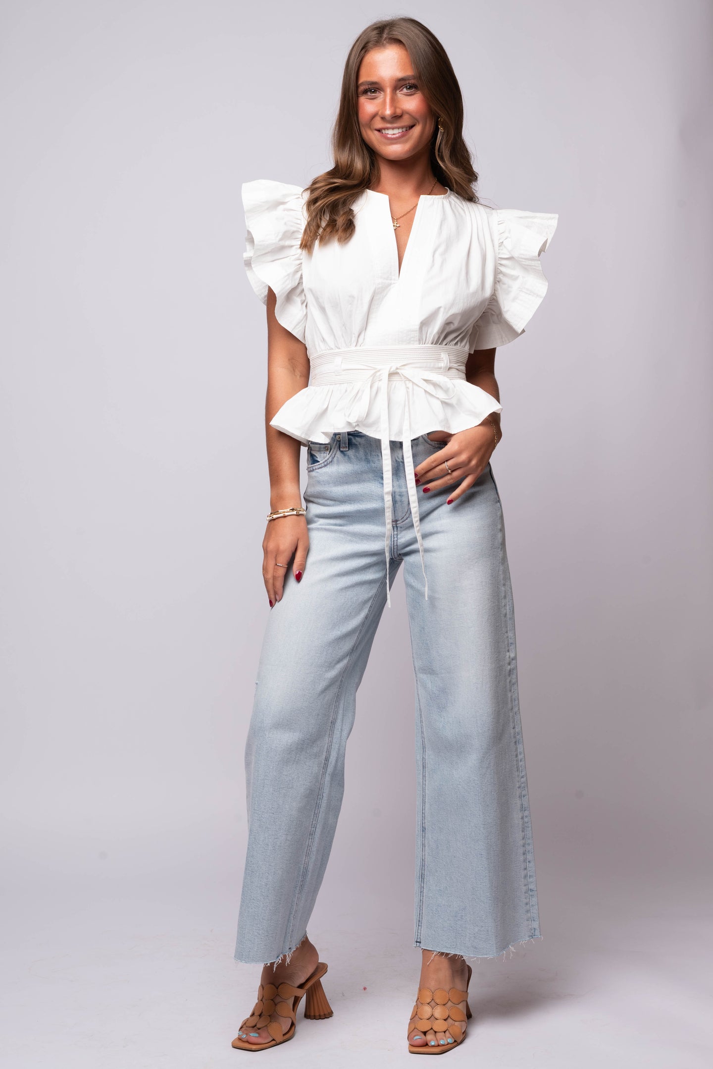 white flutter sleeve peplum top with split neckline, cinched waist, and tie belt