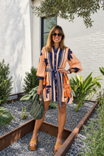 A woman wearing a peach and navy blue striped shirt dress with floral patterns by Entro