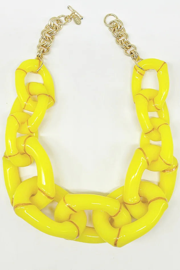 Bold yellow bamboo-style statement necklace with oversized glossy links and gold veining on a neutral bust