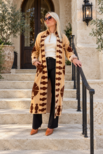 Sgt. Pepper Captain Duster in Leroy Brown, camel velvet with brown embroidery, modeled at a Mediterranean-style hotel.