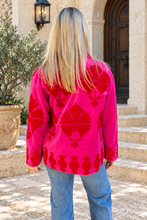 Sgt. Pepper Crew Jacket in Cherry Bomb, pink velvet with red embroidery, modeled at a Mediterranean-style hotel.