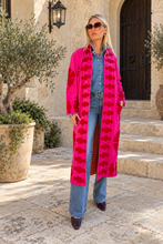 Sgt. Pepper Captain Duster in Cherry Bomb, pink velvet with red embroidery, modeled at a Mediterranean-style hotel.