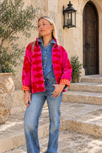 Sgt. Pepper Crew Jacket in Cherry Bomb, pink velvet with red embroidery, modeled at a Mediterranean-style hotel.