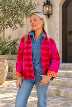 Sgt. Pepper Crew Jacket in Cherry Bomb, pink velvet with red embroidery, modeled at a Mediterranean-style hotel.